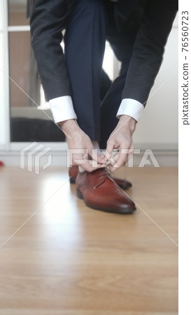 Blurred Businessman tying the shoelaces on his brown shoes Blurred Businessman tying the shoelaces on his brown shoes 76560723