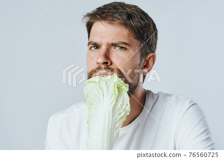 Man sitting at the table healthy eating vegetables white t-shirt diet light background Man sitting at the table healthy eating vegetables white t-shirt diet light background 76560725