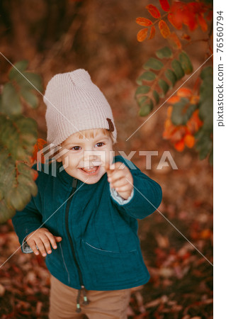 The happy child is coming. A boy dressed in a green jacket and brown trousers. 76560794
