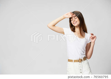 Happy woman in a white T-shirt holds a hand near the forest and smiles Happy woman in a white T-shirt holds a hand near the forest and smiles 76560795