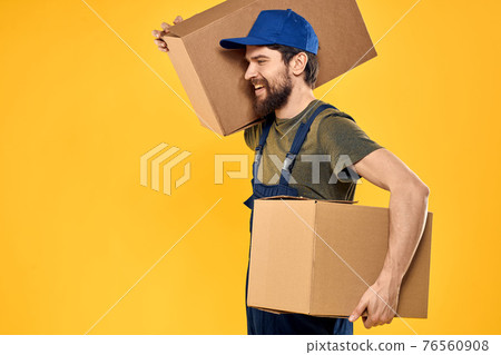 A man in a working form a box with loading tools yellow background A man in a working form a box with loading tools yellow background 76560908
