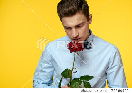 Portrait of a man with a red rose on a yellow background and a light shirt bow tie gentleman 76560921