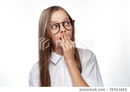 Girl in white shirt and glasses gestures with hand emotions light background studio Girl in white shirt and glasses gestures with hand emotions light background studio 76561668