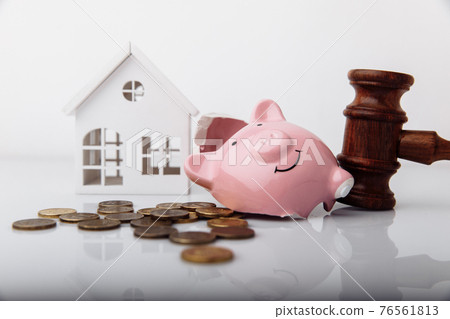 Wooden gavel, broken piggy bank and house model with coins close-up. Auction and bankruptcy concept Wooden gavel, broken piggy bank and house model with coins close-up. Auction and bankruptcy concept 76561813