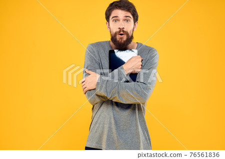 Emotional man with tablet in hands technology internet device lifestyle yellow background Emotional man with tablet in hands technology internet device lifestyle yellow background 76561836