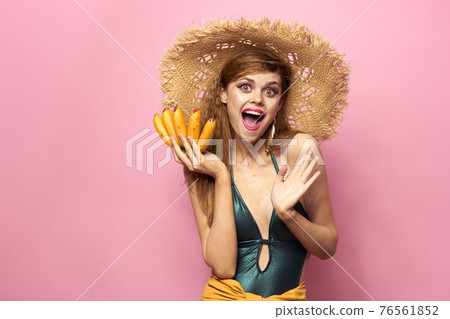 Woman in beach straw hat bananas holding fruits Exotic swimsuit pink background 76561852