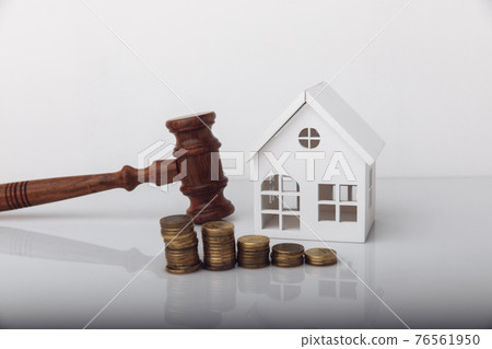 Real estate sale auction concept. Wooden gavel and house model with coins 76561950