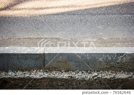 Asphalt Surface Separated By Concrete Border. Road And Sidewalk Divided By Newly Installed Concrete Curb Asphalt Surface Separated By Concrete Border. Road And Sidewalk Divided By Newly Installed Concrete Curb 76562646