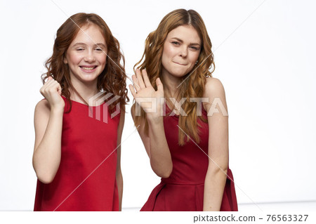 Cheerful mom and daughter next to red dresses hugs lifestyle light background smile Cheerful mom and daughter next to red dresses hugs lifestyle light background smile 76563327