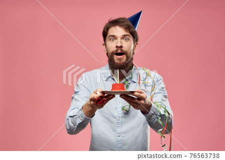Man with cake in a plate and in a blue shirt on a pink background birthday holidays cropped view Man with cake in a plate and in a blue shirt on a pink background birthday holidays cropped view 76563738