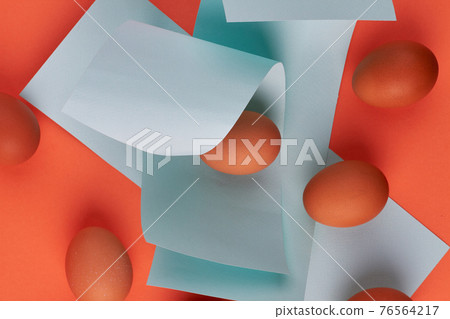 Chicken eggs and blue paper pieces. 76564217