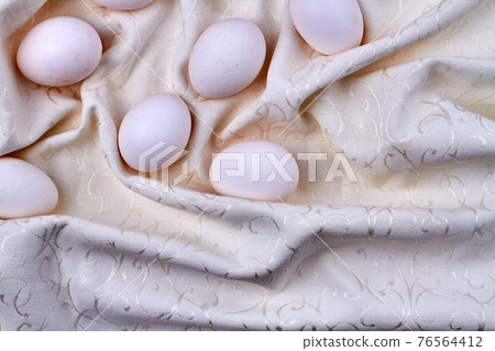 Eggs on a wrinkled ornamented textile cloth. Eggs on a wrinkled ornamented textile cloth. 76564412