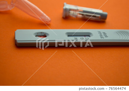 test for coronavirus on an orange background. on a matte background, a sensitive strip for coronavirus, a lancet, a container for saline. home test kit for coronavirus, a drop of blood on the test 76564474