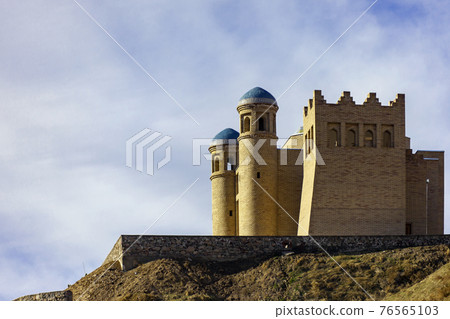 An ancient fortress on a hillside against the sky in the mountains. 76565103