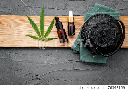 Vintage teapot with cannabis herbal tea and fresh marijuana leaves set up on concrete background. Vintage teapot with cannabis herbal tea and fresh marijuana leaves set up on concrete background. 76567169