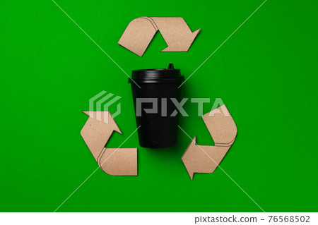 Disposable coffee cup and recycling sign on green background 76568502
