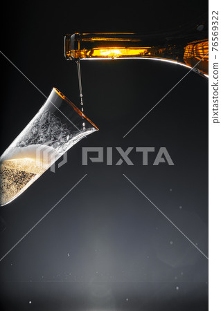Champagne pouring into glass on black background Champagne pouring into glass on black background 76569322