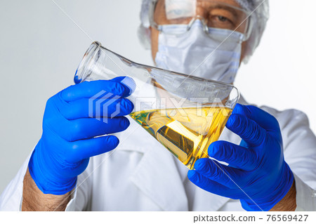 Scientist hands holding some liquid in a glassware in laboratory for analysis 76569427