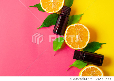 Citrus essential oil. Sliced citrus fruit and aroma bottles on pink background Citrus essential oil. Sliced citrus fruit and aroma bottles on pink background 76569553