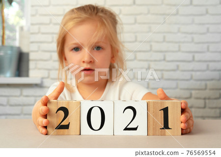 Toddler girl holding 2021 wooden cubes. Conceot of New Year 2021 Toddler girl holding 2021 wooden cubes. Conceot of New Year 2021 76569554