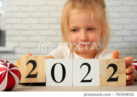 Toddler girl holding 2021 wooden cubes. Conceot of New Year 2021 Toddler girl holding 2021 wooden cubes. Conceot of New Year 2021 76569658