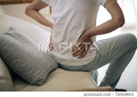 Image of a man with back pain ・ A man who puts his hand on his back Image of a man with back pain ・ A man who puts his hand on his back 76569663