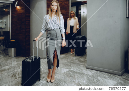 Two young women in formal clothes entering hotel lobby 76570277