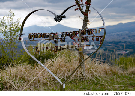 An eternal key heart-shaped swearing in front of the magnificent scenery 76571073