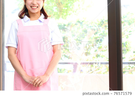 一個女人帶著微笑在她的圍裙 一個女人帶著微笑在她的圍裙 76571579