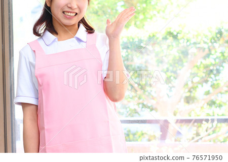 A young woman in an apron to guide 76571950