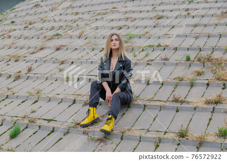 Beautiful woman sits on concrete structures in Beautiful woman sits on concrete structures in 76572922