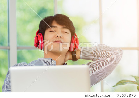 business man smile listening music in red headphone at home office 76573879