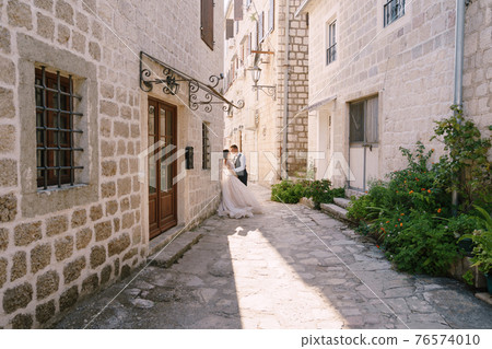 Wedding couple on the street of the old city, among ancient houses. Fine-art wedding photo in Montenegro, Perast. 76574010
