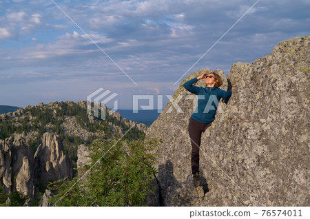 Happy emotions of a female tourist on the top of a cliff 76574011