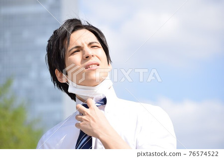 A young man who is hot and takes off his mask and looks up at the sky A young man who is hot and takes off his mask and looks up at the sky 76574522