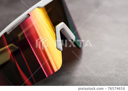 Sports glasses with a red mirrored lens and white frames on a black background 76574658