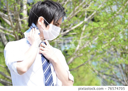 一個年輕人因為口罩悶,用手帕擦汗 一個年輕人因為口罩悶,用手帕擦汗 76574705