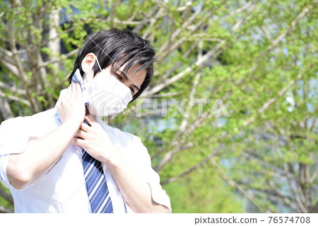 一個年輕人因為口罩悶,用手帕擦汗 一個年輕人因為口罩悶,用手帕擦汗 76574708