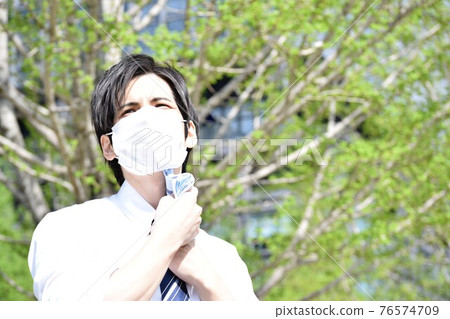 一個年輕人因為口罩悶,用手帕擦汗 一個年輕人因為口罩悶,用手帕擦汗 76574709