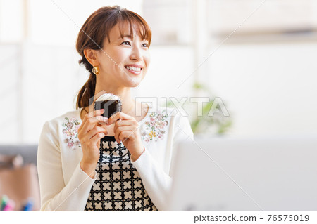 一個女人在明亮的房間裡吃飯糰 76575019