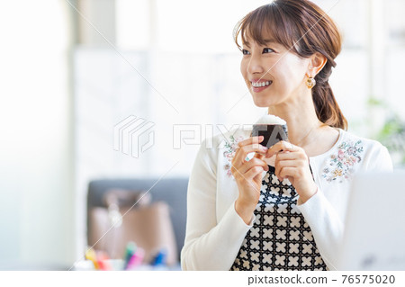 A woman eating rice balls in a bright room 76575020