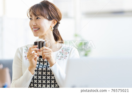 A woman eating rice balls in a bright room 76575021
