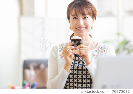 一個女人在明亮的房間裡吃飯糰 一個女人在明亮的房間裡吃飯糰 76575022