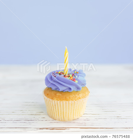 Birthday greeting concept. Yellow candle on muffin, cupcake. Blue background 76575488