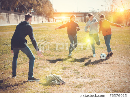 Cheerful teen friends playing with ball outdoors Cheerful teen friends playing with ball outdoors 76576915