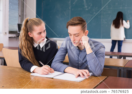 Young guy and girl students doing lesson in classroom 76576925