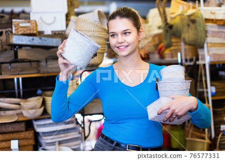 Female teenager and assortment of wicker basket in decor store Female teenager and assortment of wicker basket in decor store 76577331