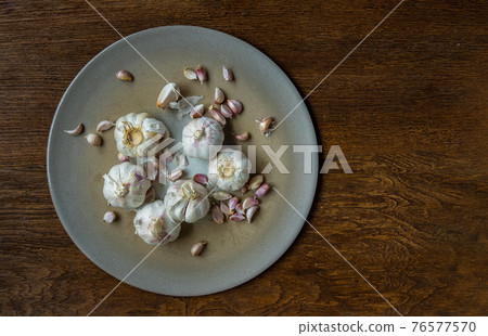 Garlic bulbs and Garlic cloves in Ceramic plate on Wooden rustic table. Garlic bulbs and Garlic cloves in Ceramic plate on Wooden rustic table. 76577570