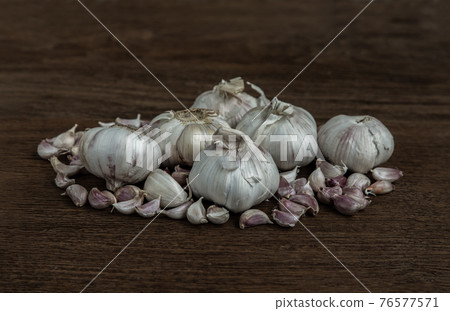 Garlic bulbs and Garlic cloves on Wooden rustic table. Garlic bulbs and Garlic cloves on Wooden rustic table. 76577571