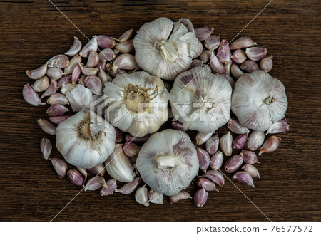 Garlic bulbs and Garlic cloves on Wooden rustic table. Garlic bulbs and Garlic cloves on Wooden rustic table. 76577572